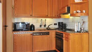 A kitchen with wooden cabinets, a dishwasher, a stove, and a microwave. -  single-storey quiet apartment with garden in a central location of Greetsiel (Greetsiel)