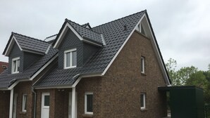 A two-story house with a brick facade and dark grey roof tiles. - modern, central, quiet area New semi-detached house with a view of the countryside (Horumersiel)