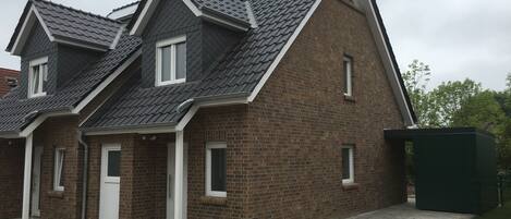 A two-story house with a brick facade and dark grey roof tiles.
