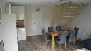 A compact kitchen with white cabinets, a wooden countertop, and a dining area with a wooden table and chairs. A staircase leads to an upper level. - modern, central, quiet area New semi-detached house with a view of the countryside (Horumersiel)