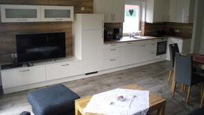 A modern kitchen with white cabinets, a built-in oven, and a large flat-screen TV. - modern, central, quiet area New semi-detached house with a view of the countryside (Horumersiel)