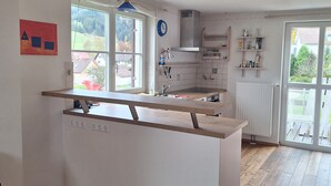 Een moderne keuken met een centraal eiland, grote ramen en uitzicht op de omgeving.