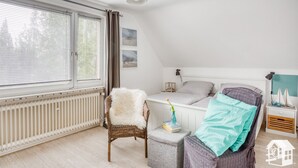 Makuuhuone, jossa on sänky, tuoli, yöpöytä ja ikkuna, jossa on sälekaihtimet.