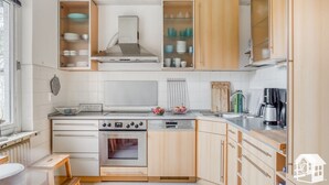 Kompakti keittiö, jossa on puiset kaapit, sisäänrakennettu uuni, pesuallas ja kahvinkeitin.