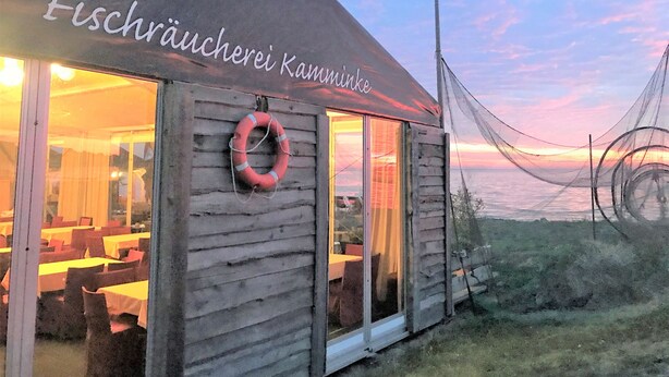 Un edificio de madera con un letrero que dice "Fischräucherei Kamminke".