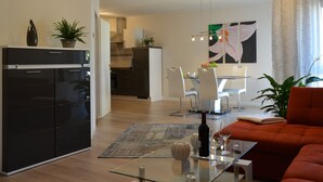 Una cocina moderna con armarios negros, un comedor con mesa de vidrio y una sala de estar con sofá rojo.