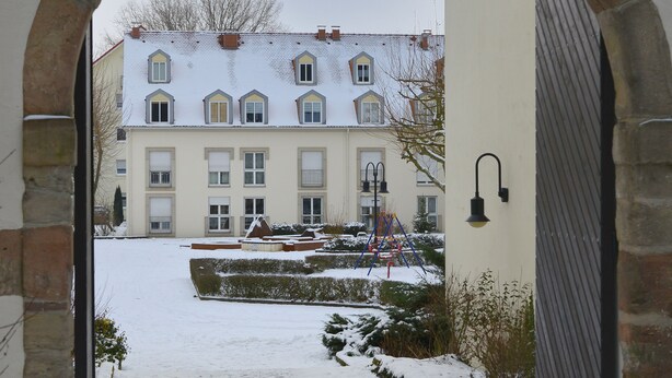 Un patio cubierto de nieve con un edificio al fondo.