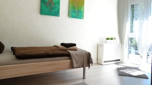 Un dormitorio minimalista con una cama, un radiador y dos cuadros abstractos en la pared.