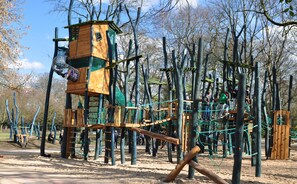 Ein Spielplatz mit einer Holz-Kletterkonstruktion, Seilen und einem Netzbereich.