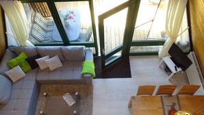 Un vaste espace de vie comprenant un canapé gris, une table basse et une table à manger en bois avec des chaises.