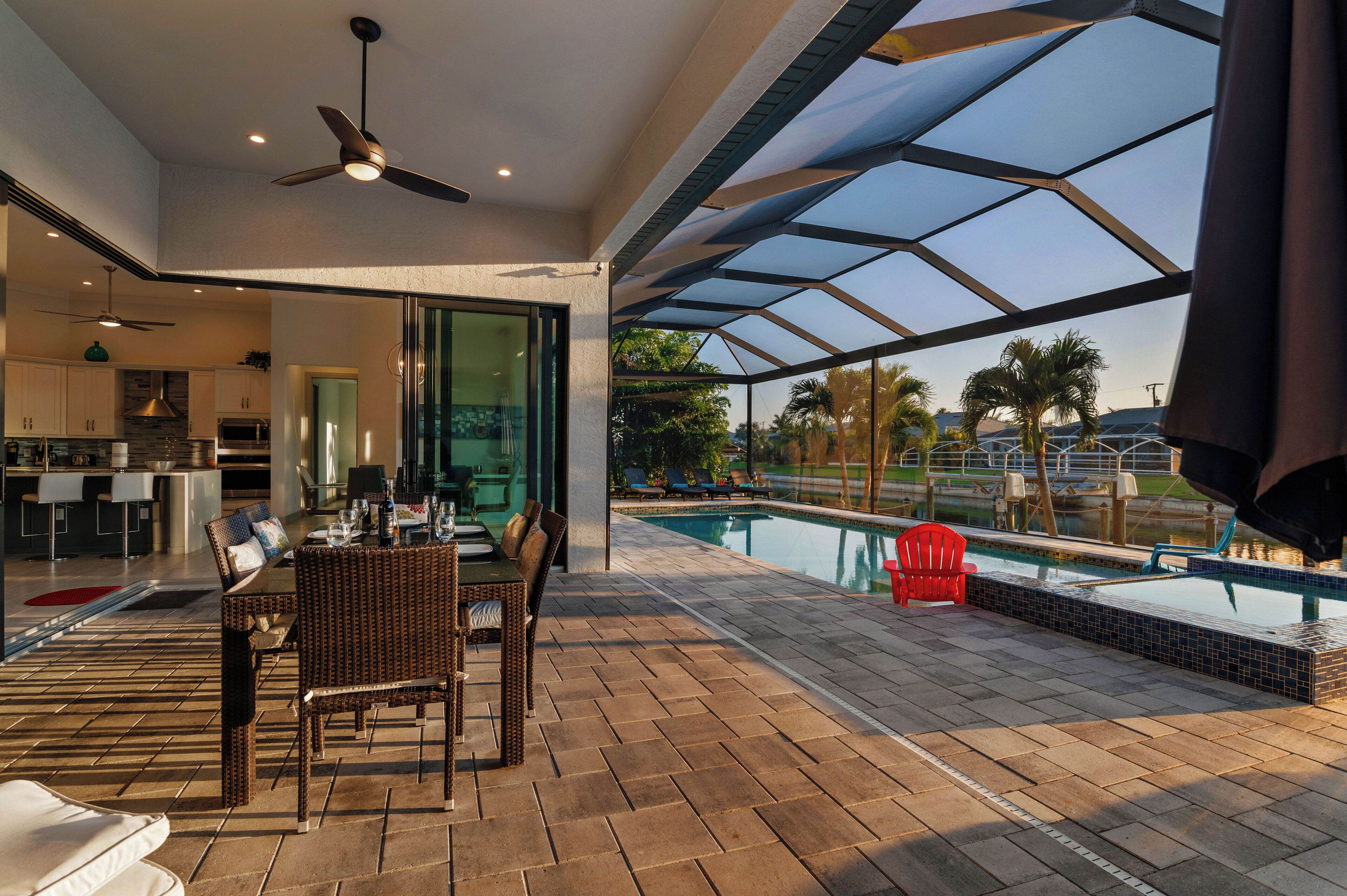 A modern outdoor area with a pool, dining setup, and a covered seating area.