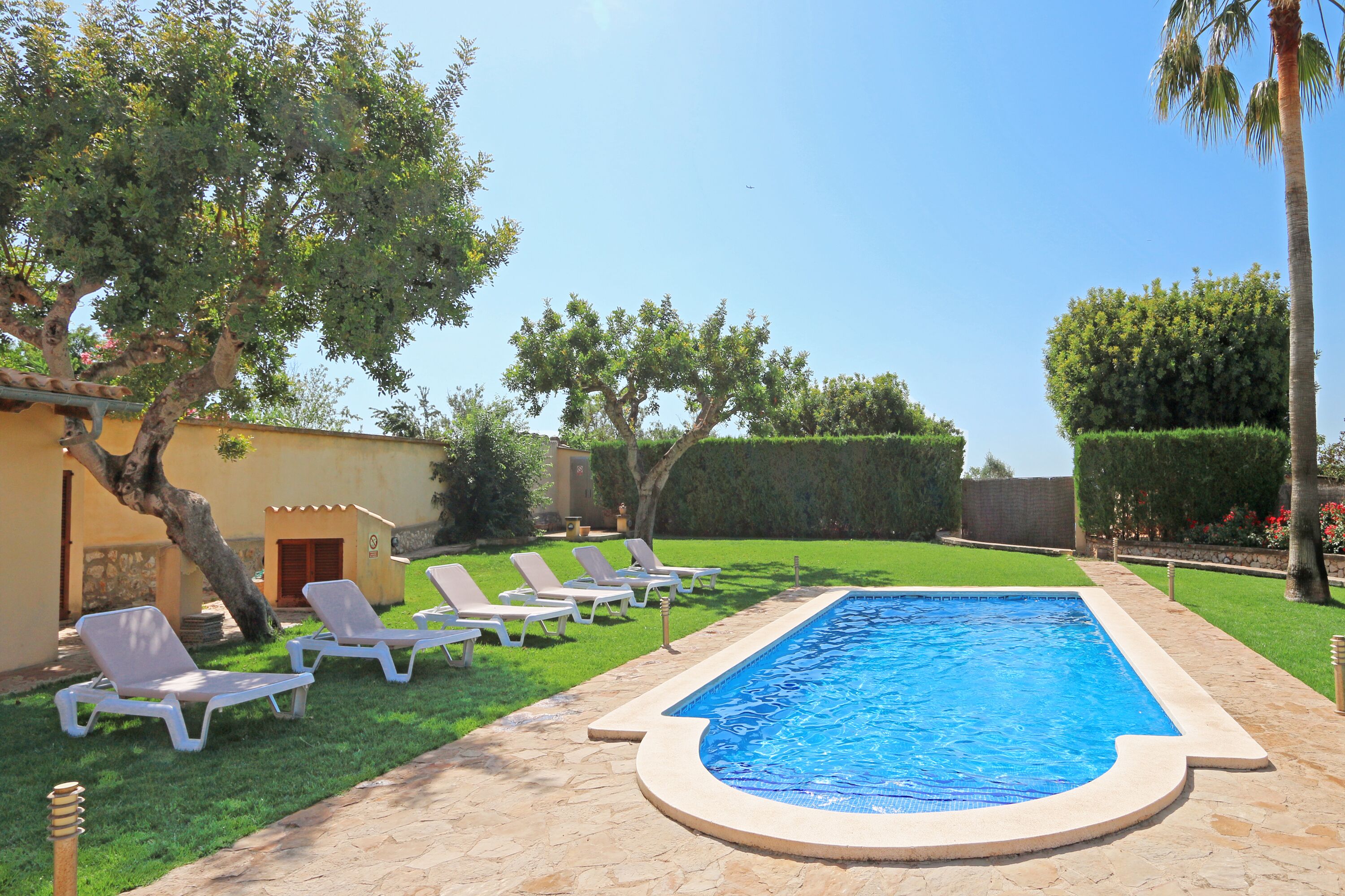 A swimming pool with lounge chairs, a stone pathway, and a well-maintained lawn.