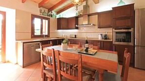 Een keuken met houten kastjes, een eettafel met stoelen, een vaatwasser en een koelkast.