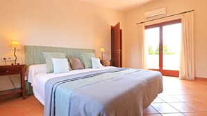 Een slaapkamer met een bed, twee nachtkastjes, een airconditioning en een schuifdeur naar buiten.