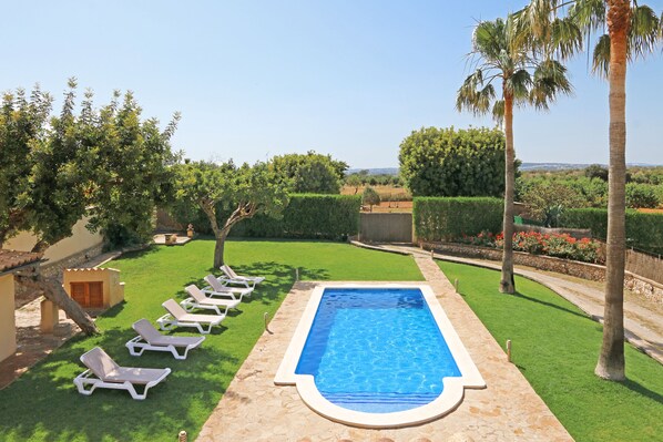 A swimming pool with lounge chairs, surrounded by well-maintained grass and palm trees. - Finca Marti Ferrer: private swimming pool, garden, barbecue, WiFi, air conditioning. (Inca)