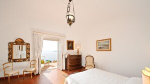 Une chambre à coucher comprenant un lit, une commode, deux chaises, un miroir et un tableau.