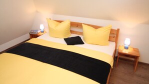 A bed with a wooden headboard, two bedside tables, and two lamps. - Seeschlößchen Thatched Cottage, "Sturmmöwe" Vacation Rental, just 200 meters from the beach (Büsumer Deichhausen)