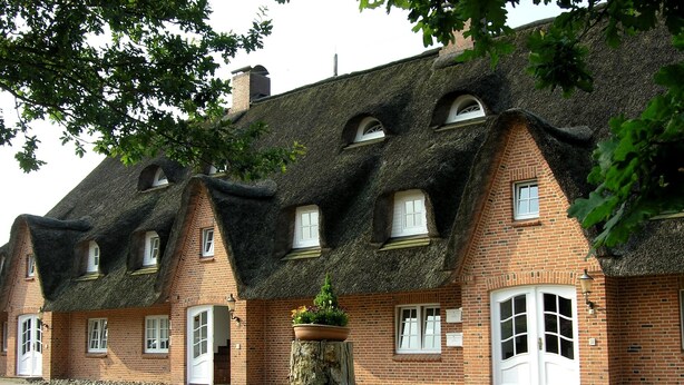 A row of traditional brick houses with thatched roofs and white doors. - Seeschlößchen Thatched Cottage, "Sturmmöwe" Vacation Rental, just 200 meters from the beach (Büsumer Deichhausen)
