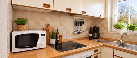 A kitchen with a microwave, stove, sink, and cabinets.