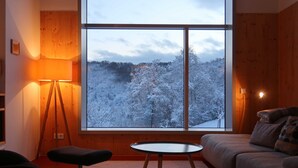 A cozy room with a large window, a floor lamp, a small table, and a sofa. - Architect-designed house, wooden house on a 10,000 m² lot of meadows and woods with a panoramic view (Schutz)