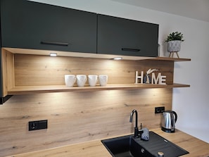 A modern kitchen with wooden shelves, a sink, and a kettle. - Sulzbergeck Vacation Rental, 60 square meters. Located in the heart of Schönau with a magnificent view of the Watzmann. (Schönau)