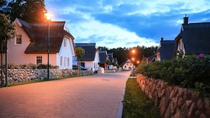 En asfalterad gata kantad av traditionella hus, stenmurar och gatlyktor.