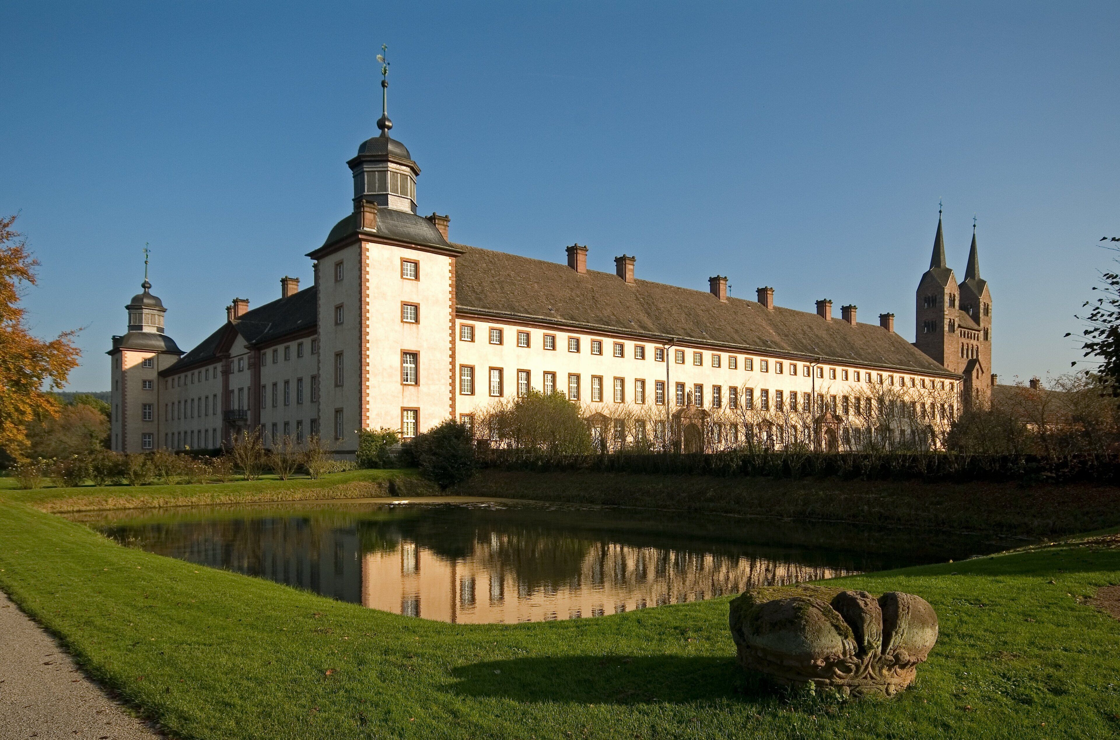 Ein großes, historisches Gebäude mit einer symmetrischen Fassade, einem zentralen Innenhof und einem Teich.