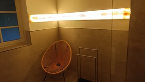 A corner room with a chair, a radiator, and a window.