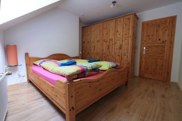Un dormitorio con cama de madera, un armario y un radiador.