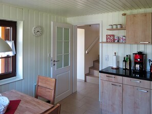 Eine Küche mit Holzausstattung, einer Kaffeemaschine und einer Uhr an der Wand.