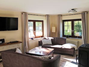Ein Wohnzimmer mit Flachbildfernseher, einer Couch, einem Couchtisch und einem Kamin.