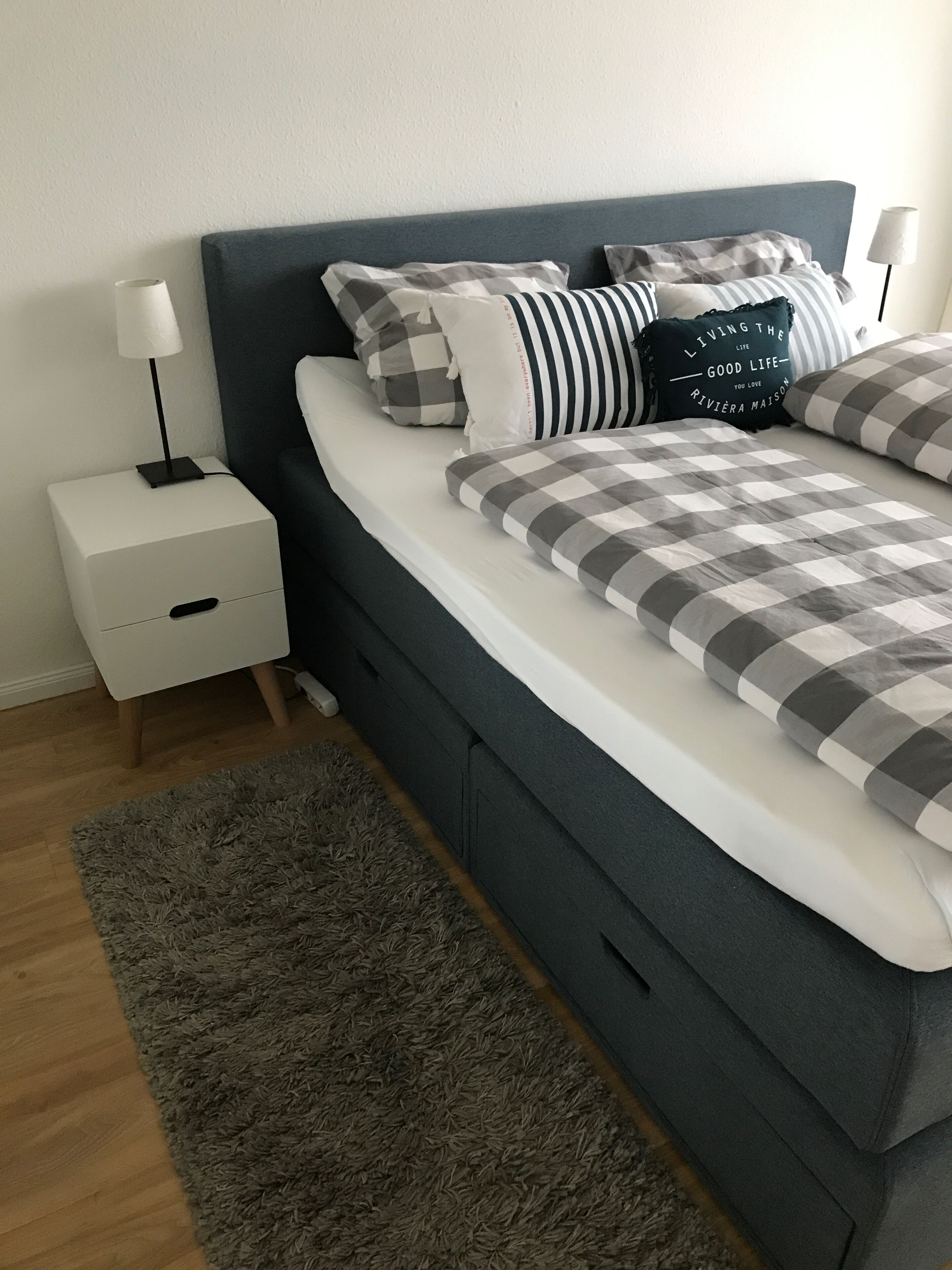 A modern bedroom with a bed, nightstand, and a gray rug.