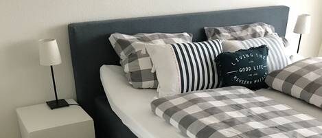 A modern bedroom with a bed, nightstand, and a gray rug.
