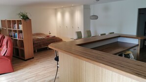 A modern bedroom with a wooden bed, a bookshelf, a desk, and a dining area.