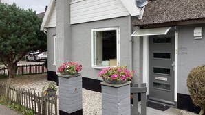 A two-story house with a grey facade, a tiled roof, and a small porch area with flower planters. - House for 5 persons, old farmhouse with luxe bathroom, 3 sleeping rooms (Groet)