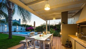 Eine Terrasss mit Pool, Holzdeck und überdachter Sitzgruppe mit Tisch und Stühlen.