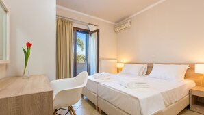 Ein Hotelzimmer mit Bett, Nachttischen, Schreibtisch, Stuhl und einem fensterbepflanzten Fenster.