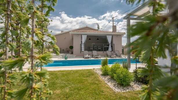 Ein Haus mit Swimmingpool, überdachter Terrasse und Garten.