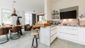 Une cuisine moderne avec des meubles blancs, un grand îlot central et un coin repas équipé de tabourets de bar.