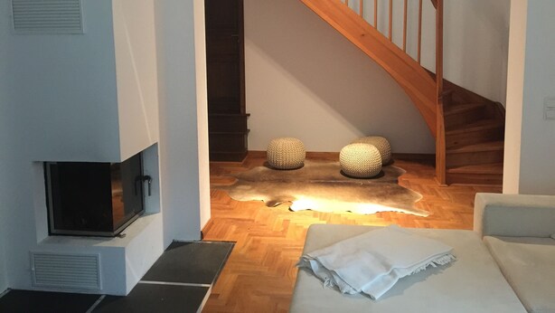 A staircase with wooden railings leading to a dark staircase. There are two woven poufs on the floor and a white blanket on a couch. - Cozy Swedish house with fireplace, sauna, winter gardens, WLAN New!!! (Biendorf)