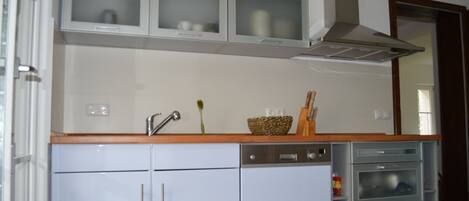 A compact kitchen with white cabinets, a built-in oven, and a microwave.