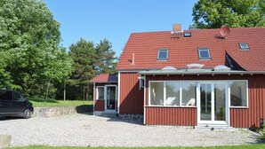 A red-roofed house with a gravel driveway and a lawn. - Cozy Swedish house with fireplace, sauna, winter gardens, WLAN New!!! (Biendorf)