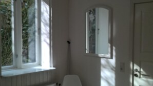 A room with a large window, a radiator, a white chair, and a hanging light fixture. - Located in the heart of Flensburg, in an alley next to the pedestrian zone (Flensburg)