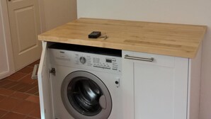A compact laundry room with a built-in washing machine and a wooden countertop. - Located in the heart of Flensburg, in an alley next to the pedestrian zone (Flensburg)