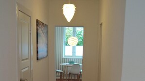 A hallway with a tiled floor, a dining area with a table and chairs, and a hanging light fixture. - Located in the heart of Flensburg, in an alley next to the pedestrian zone (Flensburg)