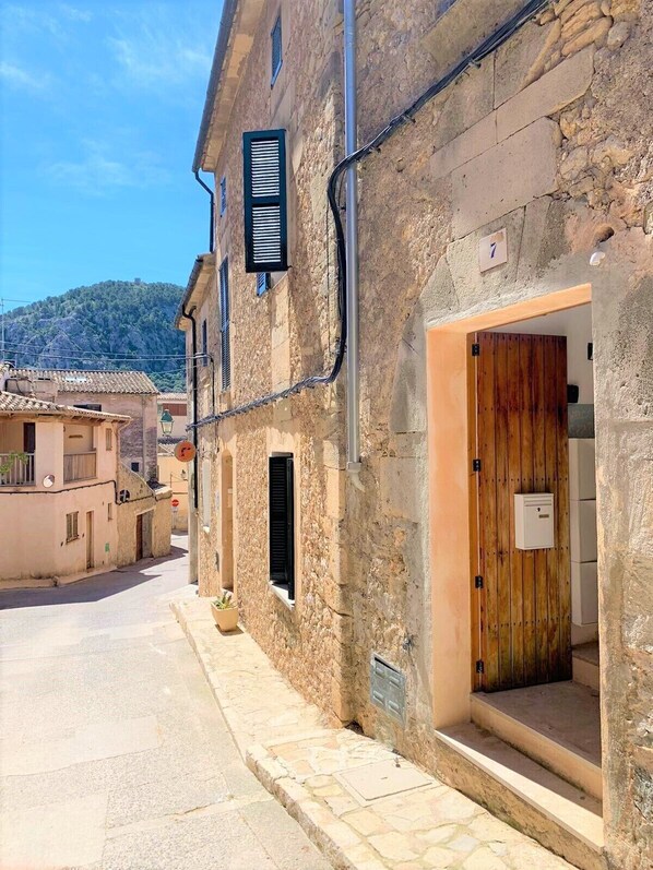 A narrow street with stone buildings, a wooden door, and a number 7 sign. - Centrally located in Pollensa with wonderful roof terrace views (Pollença)
