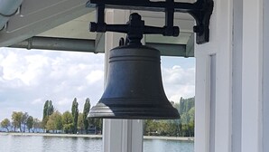 Eine Glocke an einem weißen Gebäude mit Blick auf einen See.