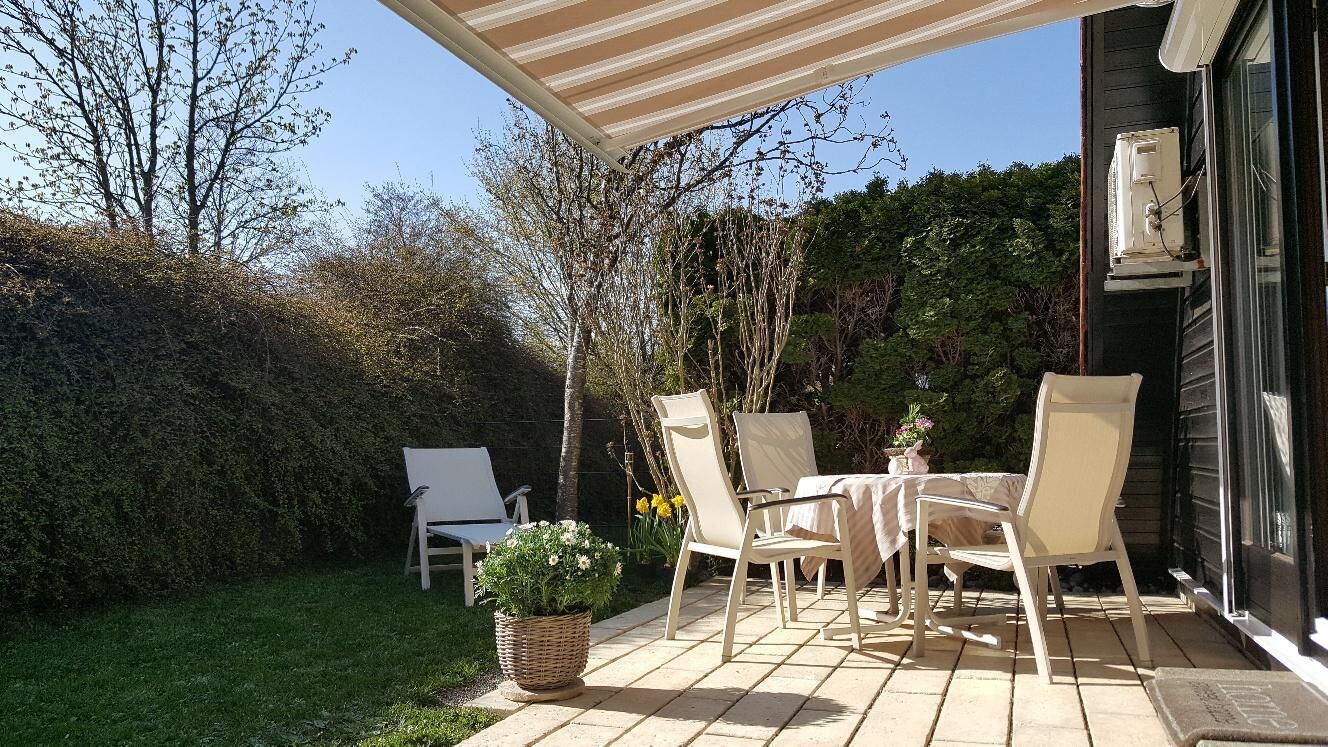 An outdoor patio with a table and chairs, a wicker basket with a plant, and a covered area.