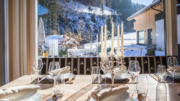 Une table à manger dressée pour un repas, avec vue sur un paysage montagneux enneigé.