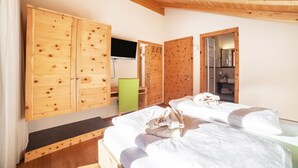 Une pièce aux murs lambrissés, comprenant un lit, un bureau et un téléviseur.